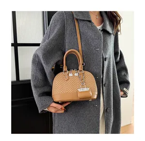 Detail of camel shell bag showing woven texture, leather handles and mini purse charm