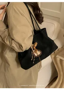 Sac fourre-tout noir minimaliste avec breloque cœur léopard porté dans un style rétro chic