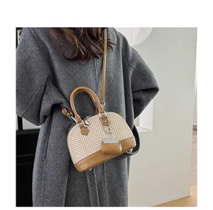 Detail of color-block shell bag with woven texture, leather trim and mini pouch charm