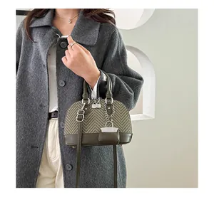 Detail of shell-shaped handbag featuring green leather and tan woven texture with chain