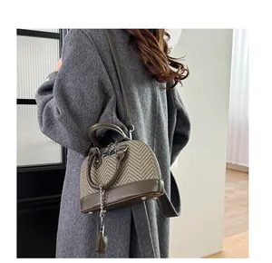 Green houndstooth shell bag worn by model showing crossbody strap and leather handle details