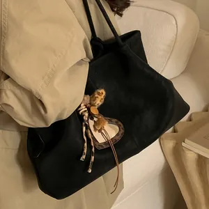 Grand sac cabas noir rétro avec pendentif léopard en forme de cœur sur un mannequin en trench