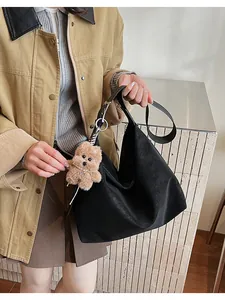 Detail of black PU leather tote bag with a cute plush bear charm and pearl decoration