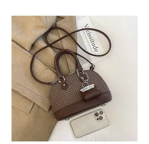 Detail view of brown houndstooth shell bag with smartphone for size reference