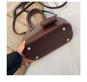 Detail of vintage shell bag showing metal base studs and premium brown leather texture