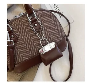 Detail view of herringbone shell bag with mini leather charm and silver hardware