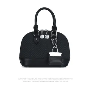 Detail view of black shell handbag featuring textured weaving and leather stitching