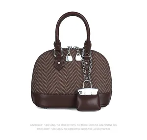 Detail of brown herringbone fabric and smooth leather texture on shell handbag