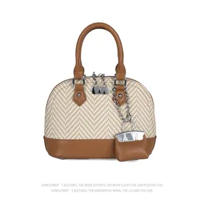 Detail view of woven shell bag with brown leather trim and metallic zipper accents