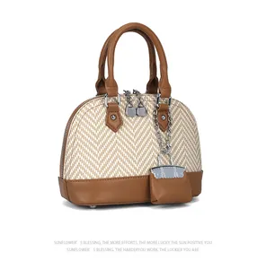 Macro detail of the woven shell bag featuring brown leather trim and mini pouch charm