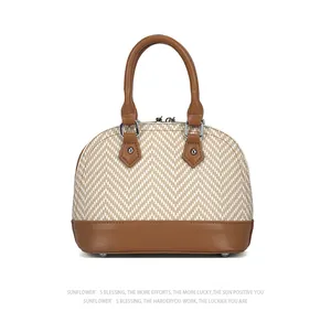 Detail view of woven shell bag with brown leather trim and silver metal protective feet