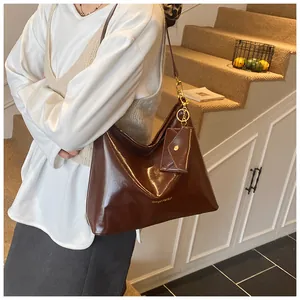 Detail einer dunkelbraunen großen Ledertasche mit goldenem Logo und kleiner Münzbörse