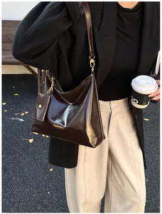 Detailaufnahme einer dunkelbraunen, glänzenden Schultertasche mit Münzbeutel und Goldbeschlägen