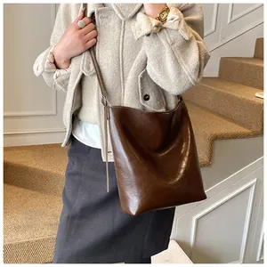 Detail of vintage coffee leather bucket bag shown with elegant office tweed outfit