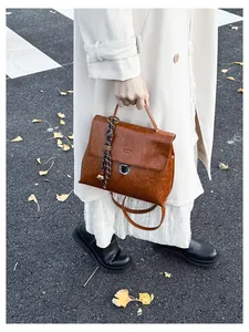 Detailansicht der braunen Vintage-Handtasche mit floralem Schal und Glockenanhänger