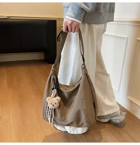 Détail du sac fourre-tout kaki avec plis, broderie du logo et breloque ourson