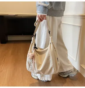 Détail du sac cabas demi-lune blanc cassé avec texture douce et breloque ourson