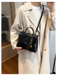 Detail einer Vintage schwarzen Kuriertasche aus Ölleder mit rundem Metallanhänger