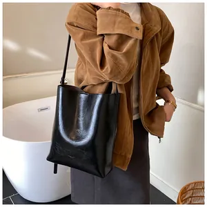 Detailed view of black patent leather shoulder bag showing glossy texture and slim strap