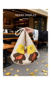 Detail of cute bear embroidery on beige knitted tote bag with leather buckle handle