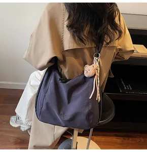 Détail du grand sac hobo bleu marine avec pendentif ours en peluche et broderie logo