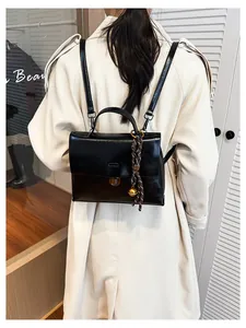Detail des schwarzen Vintage-Lederrucksacks mit Goldschnalle und geflochtenem Anhänger