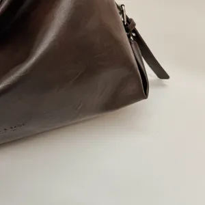 Vue macro détaillée de la texture du cuir marron foncé avec le logo E & BAGS FASHION