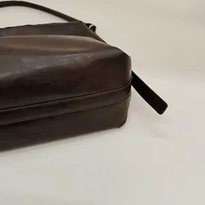 Détail du cabas en cuir marron foncé avec lettrage embossé et texture de cuir fine