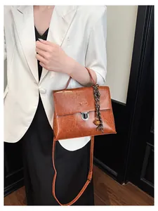 Detailansicht einer braunen Vintage-Umhängetasche mit Metallschnalle und Anhänger