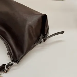 Détail du cabas en cuir marron foncé montrant le grain de cuir et la boucle argentée