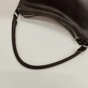Zoom sur la boucle argentée et l'attache de la bandoulière d'un sac hobo marron foncé