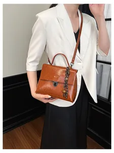 Braune Vintage-Tasche aus Kunstleder mit Metallschnalle und Anhänger an einem Model