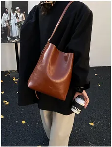 Detail view of brown vintage wax leather bucket bag worn on shoulder in autumn setting