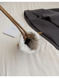 Detail of plush cream lamb wool bucket bag with contrast brown suede drawstring handle