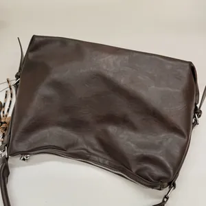 Détail d'un sac cabas en cuir PU marron avec zip métallique et pompon léopard