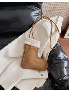 Detail view of brown plush boot-shaped crossbody bag on a white blazer background