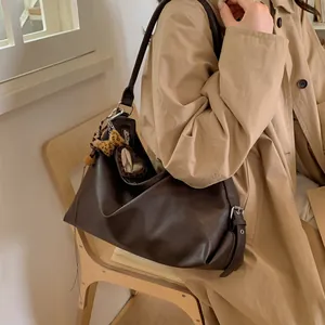 Détail du sac hobo en cuir marron foncé avec breloque cœur léopard et pompon en peluche