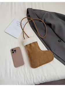 Detail view of a brown suede boot-shaped crossbody bag with white plush trim and cord strap
