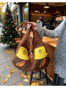 Detail of knitted tote bag showing cartoon patch embroidery and horn button closure