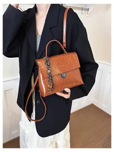 Detailaufnahme der braunen Vintage-Handtasche mit Metallschnalle und gewebtem Anhänger