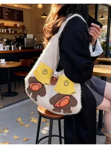 Detail of a beige knit shoulder bag with cute teddy bear embroidery in a warm cafe setting