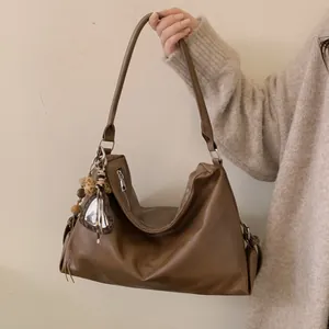 Détail d'un cabas marron en cuir souple avec breloque cœur léopard et pompon élégant