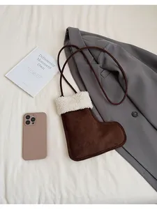 Detail of a brown suede boot-shaped crossbody bag with white faux fur trim and rope strap