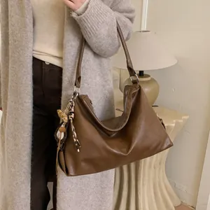 Sac cabas en cuir souple marron avec pompon léopard porté par un mannequin en intérieur
