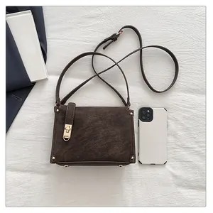 Macro shot of dark brown retro shoulder bag with gold hardware and phone for size