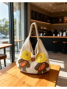 Detailed close-up of beige knitted tote bag featuring cute cartoon bear embroidery