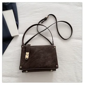 Detail of dark brown leather crossbody bag with golden twist lock and metal rivets