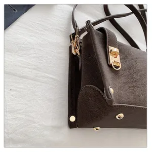 Close-up of retro brown shoulder bag showing grain leather texture and gold hardware