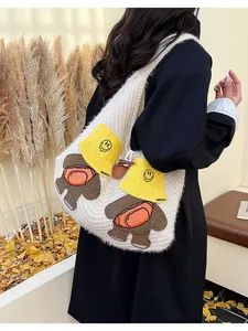 Detail of white knit tote bag featuring cute cartoon bear with yellow hat outdoors