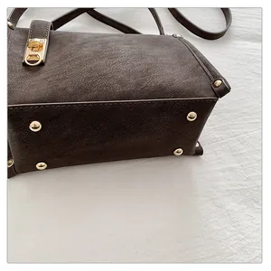 Close-up of vintage brown square bag featuring gold bottom rivets and textured leather